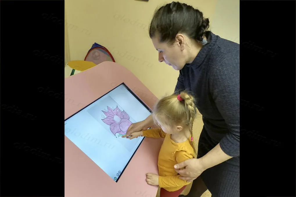 Малышка с взрослым раскрашивает цветок на сенсорном экране