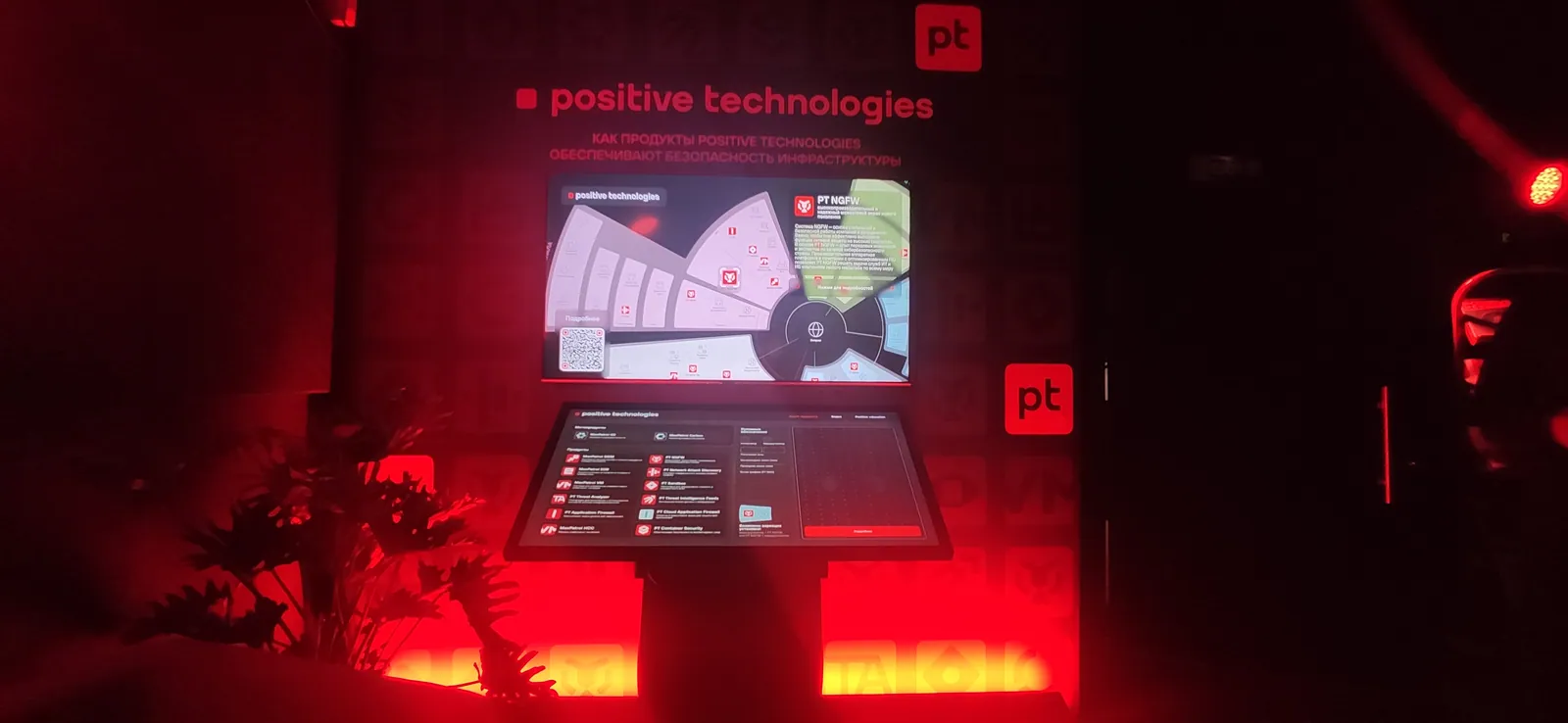 Два наклонных терминала зоны в фирменной красной подсветке стенда Positive Technologies
