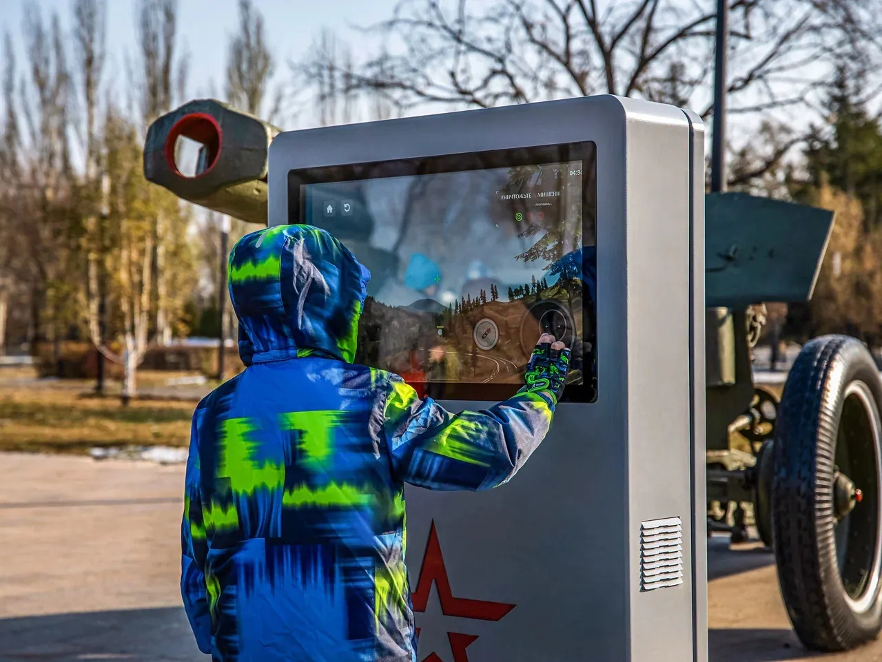 Подросток работает с сенсорным экраном терминала у гаубицы