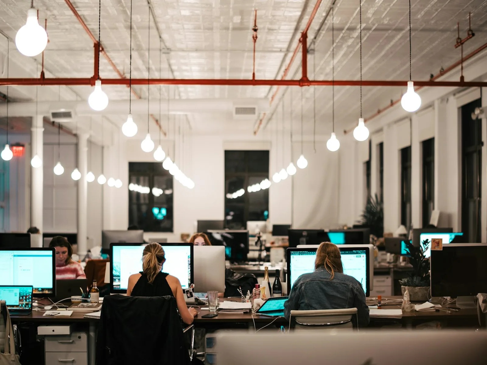 Команда разработчиков работает за мониторами в современном лофт-офисе